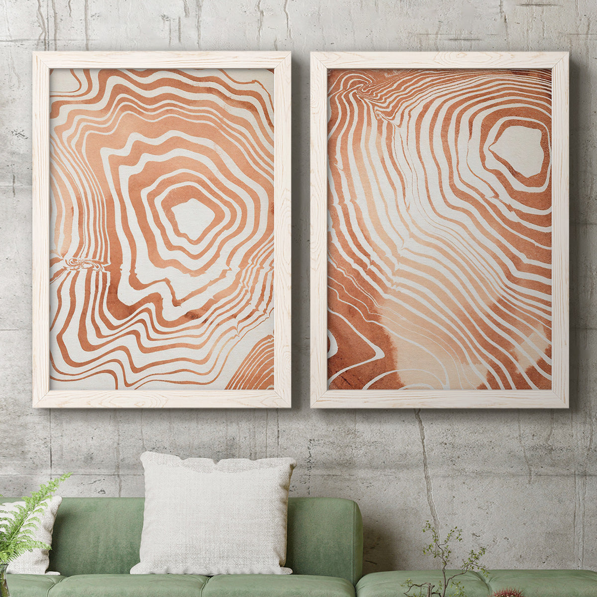 Set of two white barnwood framed canvas prints depicting a coordinated art pair of concentric wood-grain rings and rippling contour lines rendered as minimalist marbled pattern abstracts above a sofa in a modern living room.