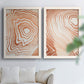 Set of two white barnwood framed canvas prints depicting warm terracotta lines, cream negative space, and organic nested curves arranged across two complementary compositions above a sofa in a bright living space.