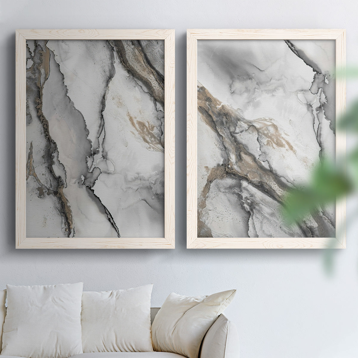 Set of two white barnwood framed canvas prints depicting fluid gray and black marbling with layered translucent forms and shimmering neutral details above a sofa in a bright living space.