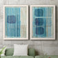Set of two white barnwood framed canvas prints depicting a coordinated art pair of stacked blue ovals behind fine vertical stripes rendered as graphic geometric abstracts above a sofa in a modern living room.
