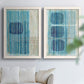 Set of two white barnwood framed canvas prints depicting navy shapes, turquoise lines, weathered texture, and pale grids arranged across two complementary compositions above a sofa in a bright living space.