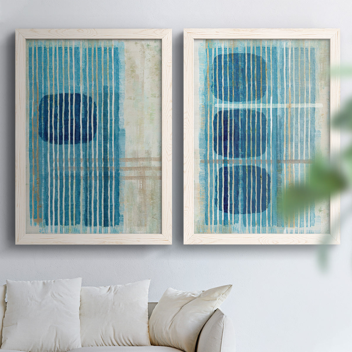 Set of two white barnwood framed canvas prints depicting navy shapes, turquoise lines, weathered texture, and pale grids arranged across two complementary compositions above a sofa in a bright living space.