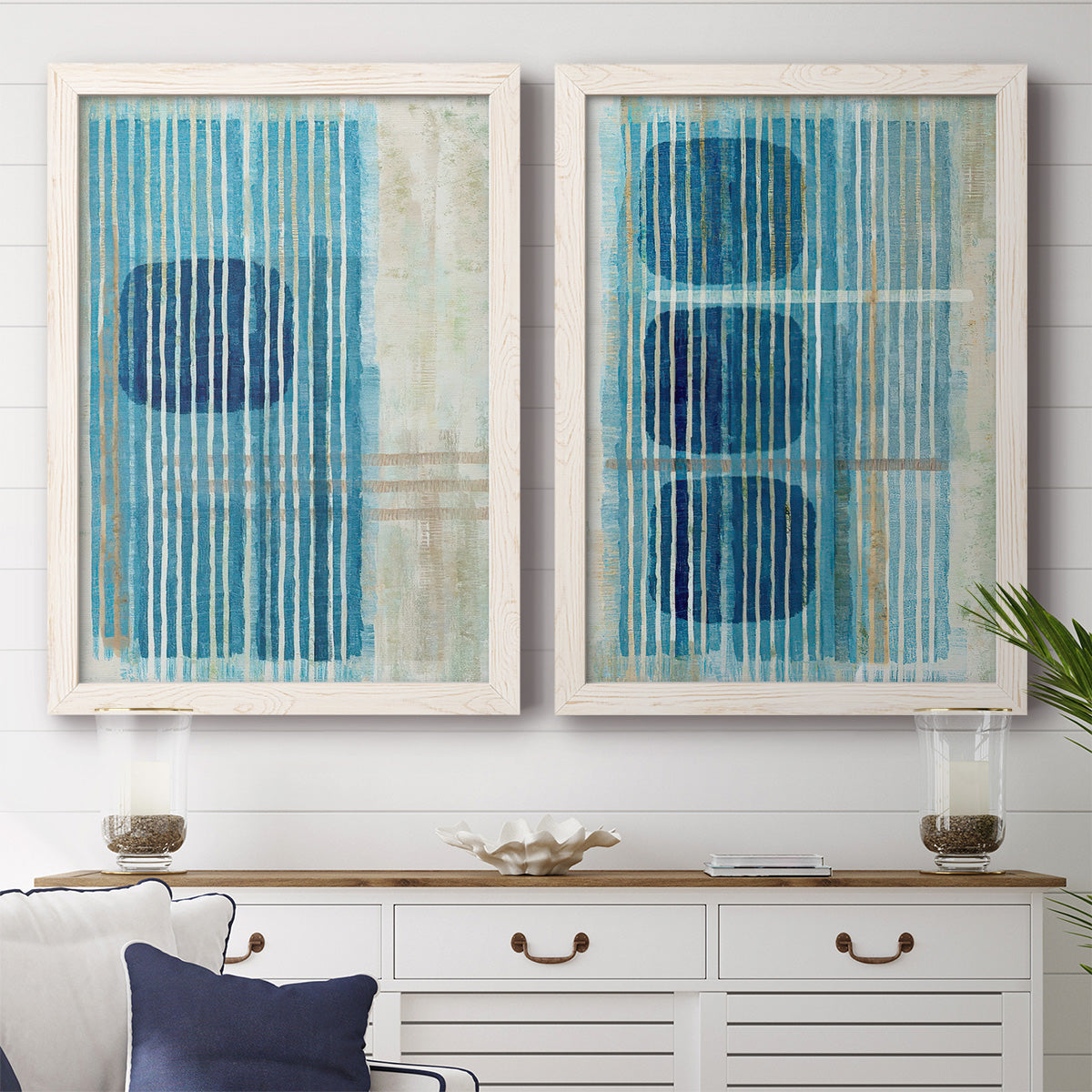 Set of two white barnwood framed canvas prints depicting a coordinated art pair of stacked blue ovals behind fine vertical stripes rendered as graphic geometric abstracts above a dining room sideboard.