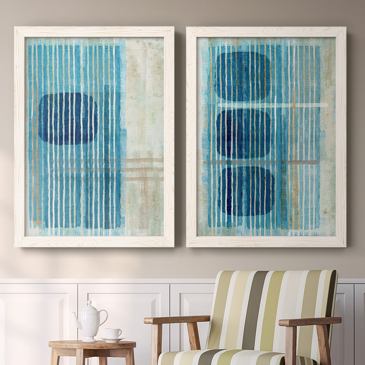Set of two white barnwood framed canvas prints depicting two graphic geometric abstracts featuring stacked blue ovals behind fine vertical stripes above a sideboard in a cozy sitting room.