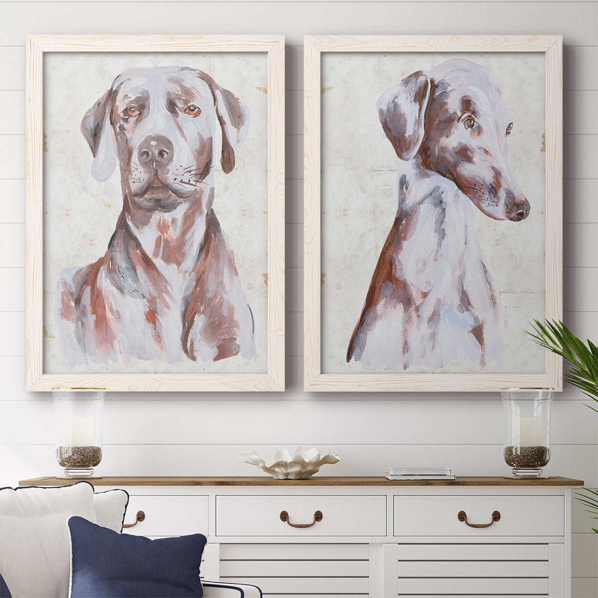 Set of two white barnwood framed canvas prints depicting a coordinated art pair of gentle seated dog portraits rendered as traditional watercolor pet paintings above a dining room sideboard.