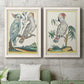 Set of two white barnwood framed canvas prints depicting a coordinated art pair of misty blue gray and violet marks hovering across pale grounds rendered as atmospheric abstract paintings above a sofa in a modern living room.