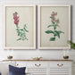 Set of two white barnwood framed canvas prints depicting antique floral illustrations featuring a tall red bloom and a clustered mauve flower above a dining room sideboard.