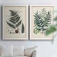 Set of two white barnwood framed canvas prints depicting varied green fronds, roots, spores, and archival labels arranged across two complementary compositions above a sofa in a bright living space.