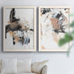 Set of two white barnwood framed canvas prints depicting sweeping brushwork, scraped passages, and layered neutral marks arranged across two complementary compositions above a sofa in a bright living space.