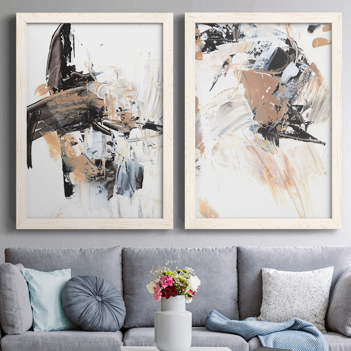 Set of two white barnwood framed canvas prints depicting paired bold mixed-media abstracts with sweeping brushwork, scraped passages, and layered neutral marks above a sofa in a contemporary living room.
