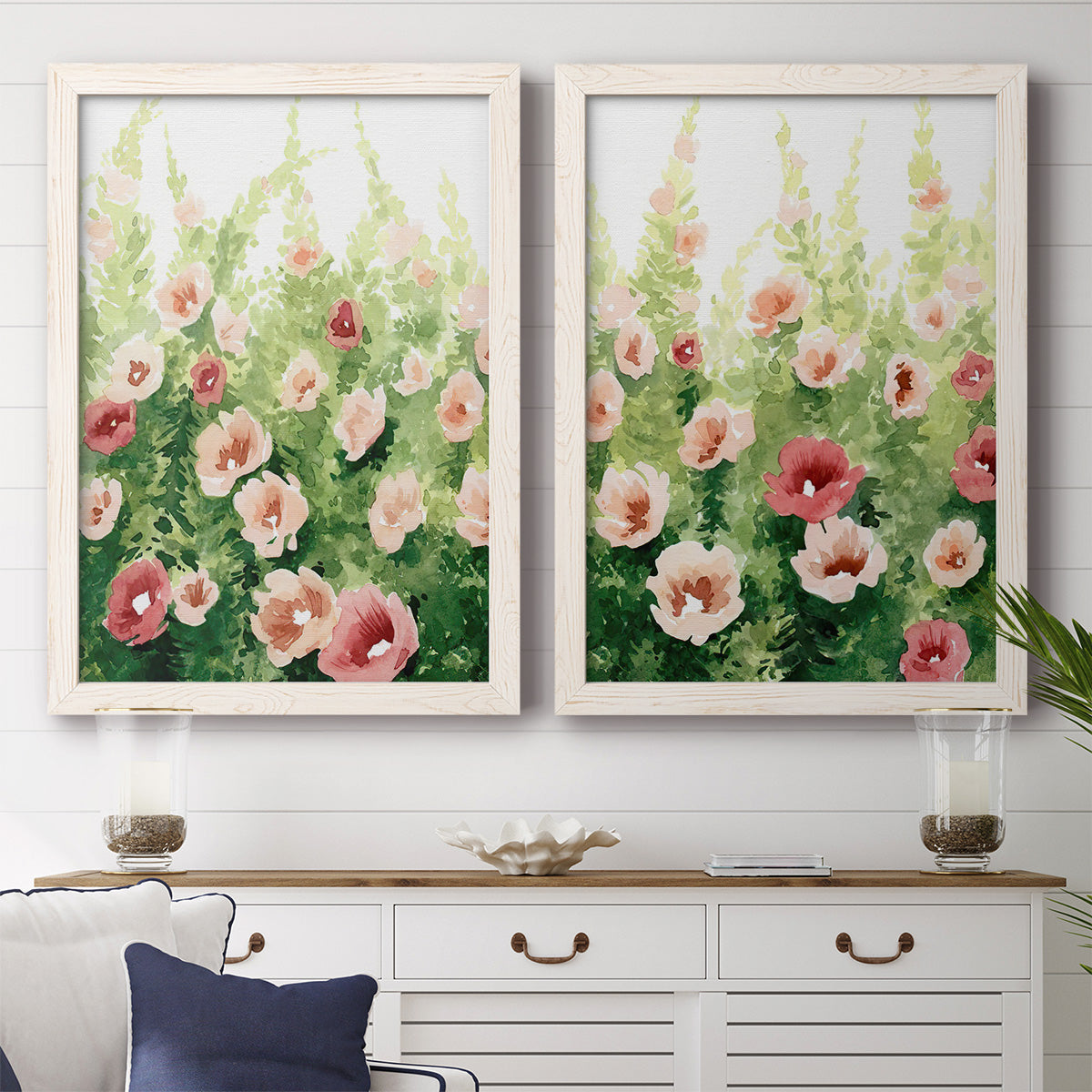 Set of two white barnwood framed canvas prints depicting a coordinated art pair of a field of pink coral and white flowers rendered as luminous impressionistic floral paintings above a dining room sideboard.