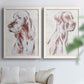 Set of two white barnwood framed canvas prints depicting soft brown and gray fur, expressive faces, and lightly distressed cream grounds arranged across two complementary compositions above a sofa in a bright living space.