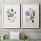 Set of two white barnwood framed canvas prints depicting a coordinated art pair of scattered translucent watercolor shapes rendered as airy minimalist abstracts above a sofa in a modern living room.
