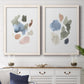 Set of two white barnwood framed canvas prints depicting a coordinated art pair of scattered translucent watercolor shapes rendered as airy minimalist abstracts above a dining room sideboard.