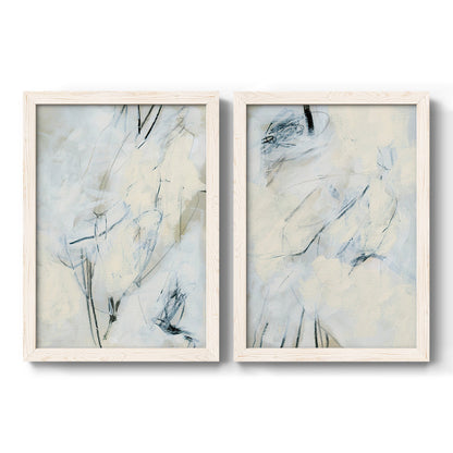 Set of two white barnwood framed canvas prints featuring two airy gestural abstracts featuring pale blue cream and charcoal marks drifting across white.