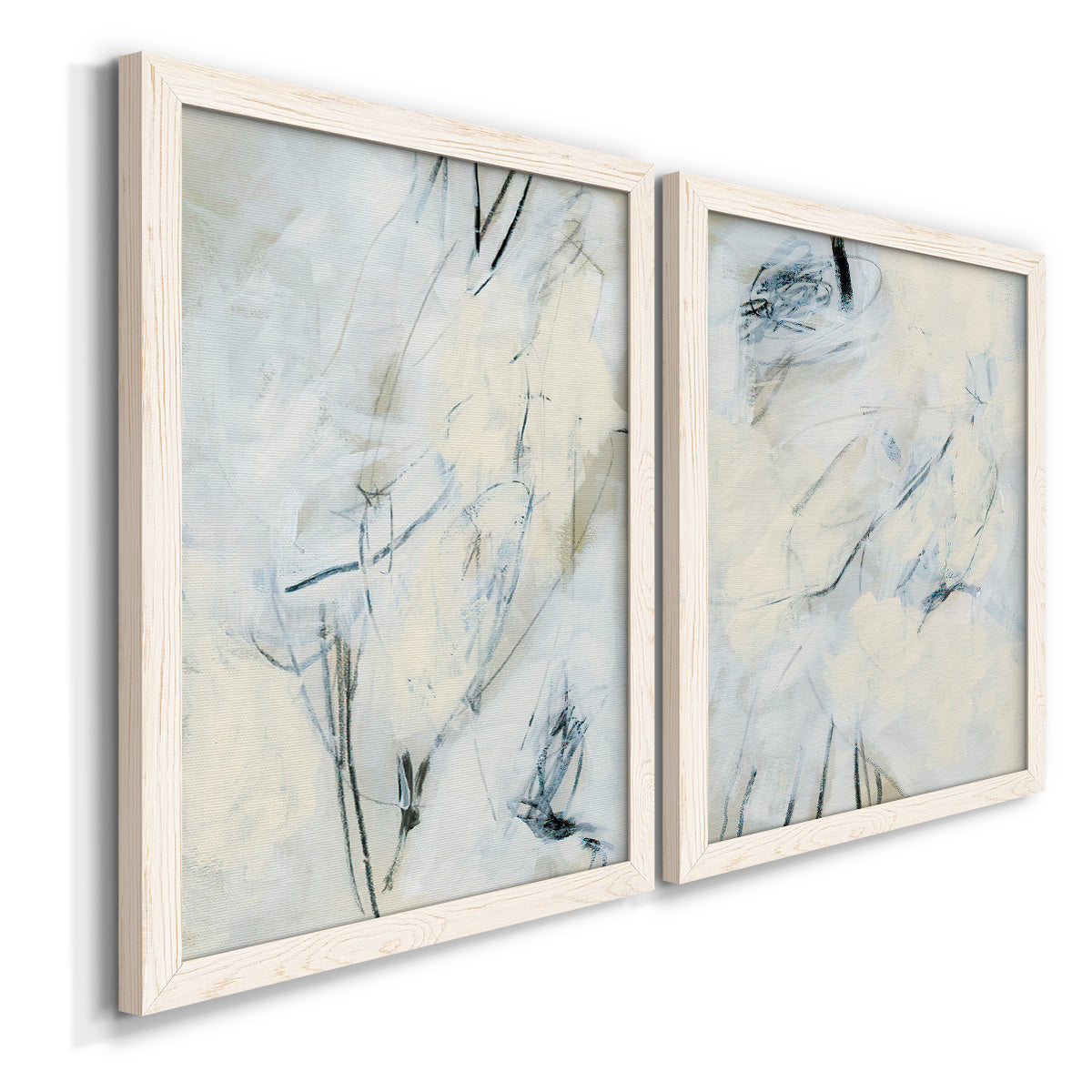 Angled view of a set of two white barnwood framed canvas prints featuring two airy gestural abstracts featuring pale blue cream and charcoal marks drifting across white.