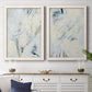 Set of two white barnwood framed canvas prints depicting a coordinated art pair of pale blue cream and charcoal marks drifting across white rendered as airy gestural abstracts above a dining room sideboard.