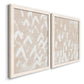 Angled view of a set of two white barnwood framed canvas prints featuring two tribal-inspired pattern abstracts featuring white hand-painted dashes arcs and chevrons.