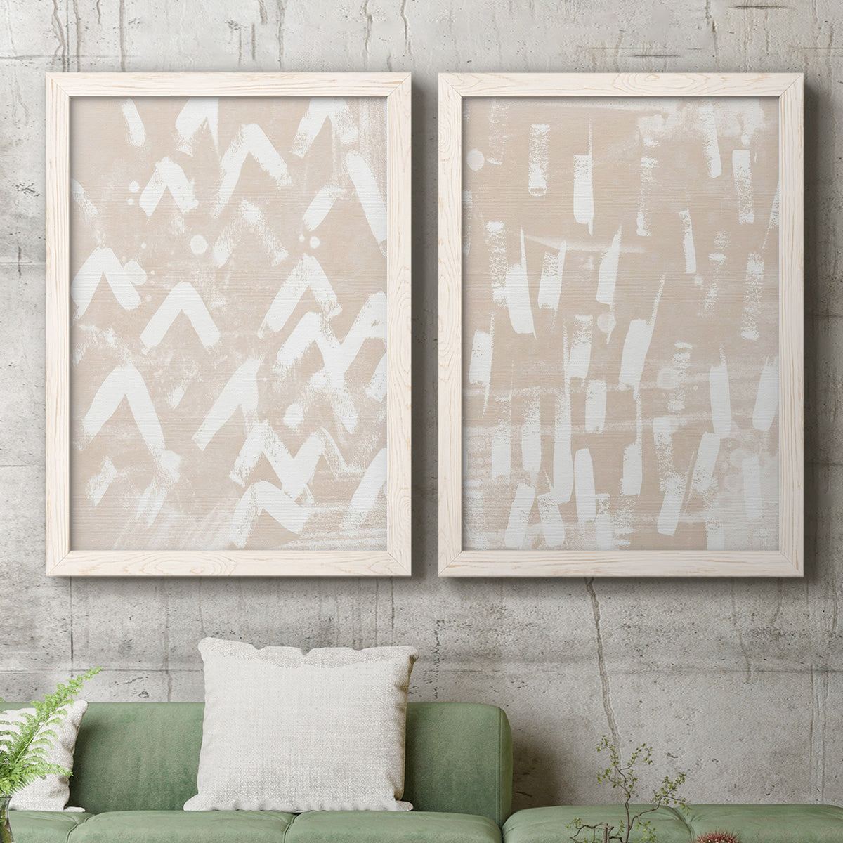 Set of two white barnwood framed canvas prints depicting a coordinated art pair of white hand-painted dashes arcs and chevrons rendered as tribal-inspired pattern abstracts above a sofa in a modern living room.