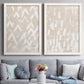 Set of two white barnwood framed canvas prints depicting paired tribal-inspired pattern abstracts with repeating marks, warm beige grounds, and block-print texture above a sofa in a contemporary living room.