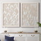 Set of two white barnwood framed canvas prints depicting a coordinated art pair of white hand-painted dashes arcs and chevrons rendered as tribal-inspired pattern abstracts above a dining room sideboard.