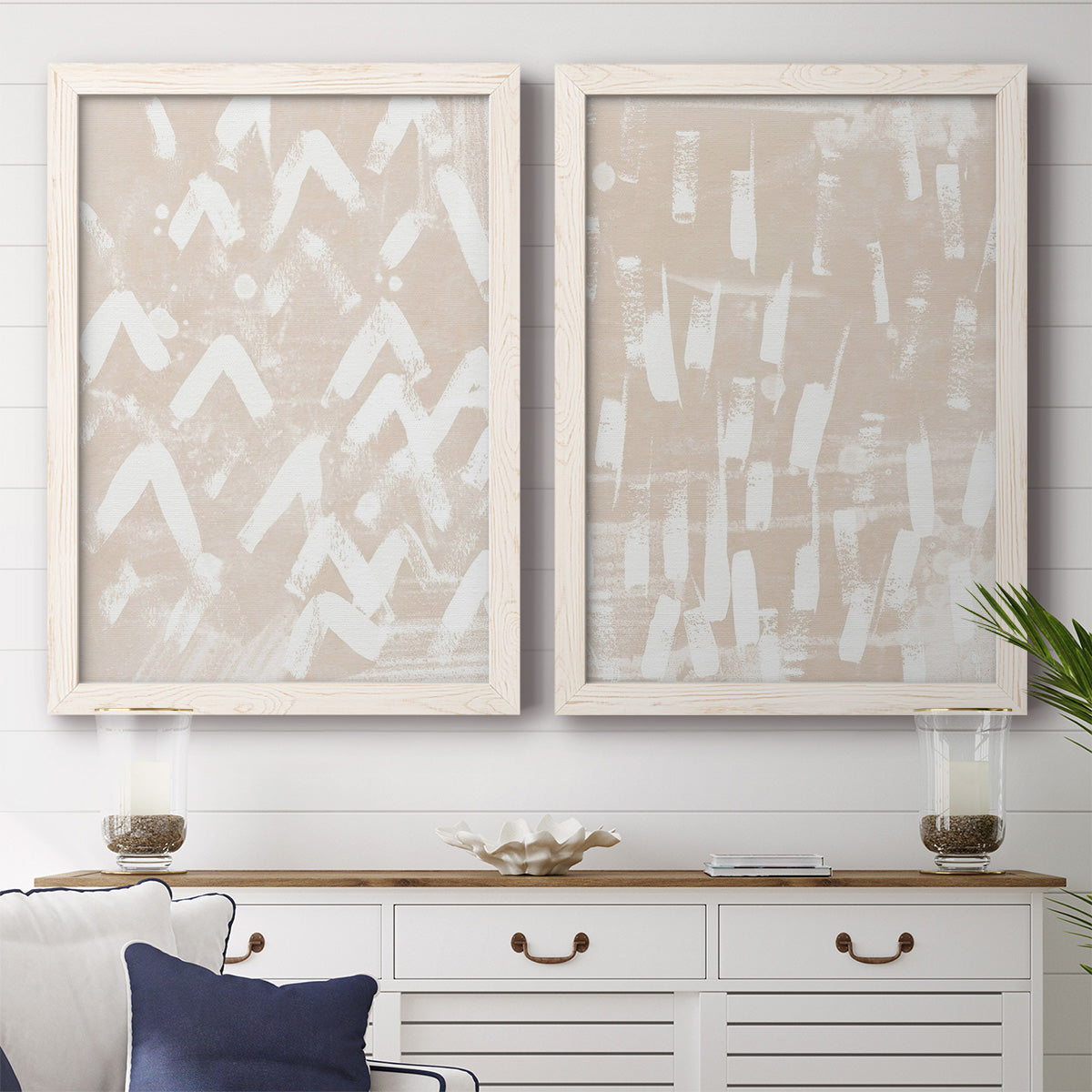 Set of two white barnwood framed canvas prints depicting a coordinated art pair of white hand-painted dashes arcs and chevrons rendered as tribal-inspired pattern abstracts above a dining room sideboard.