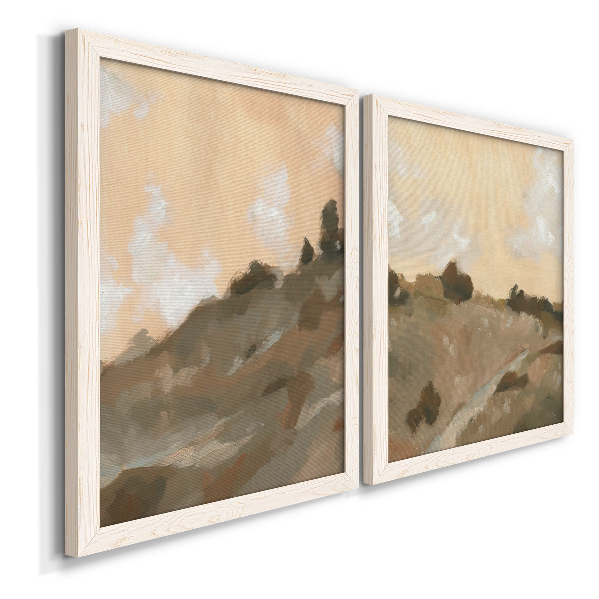 Angled view of a set of two white barnwood framed canvas prints featuring two minimalist watercolor landscapes featuring misty brown hills and winding mountain paths.