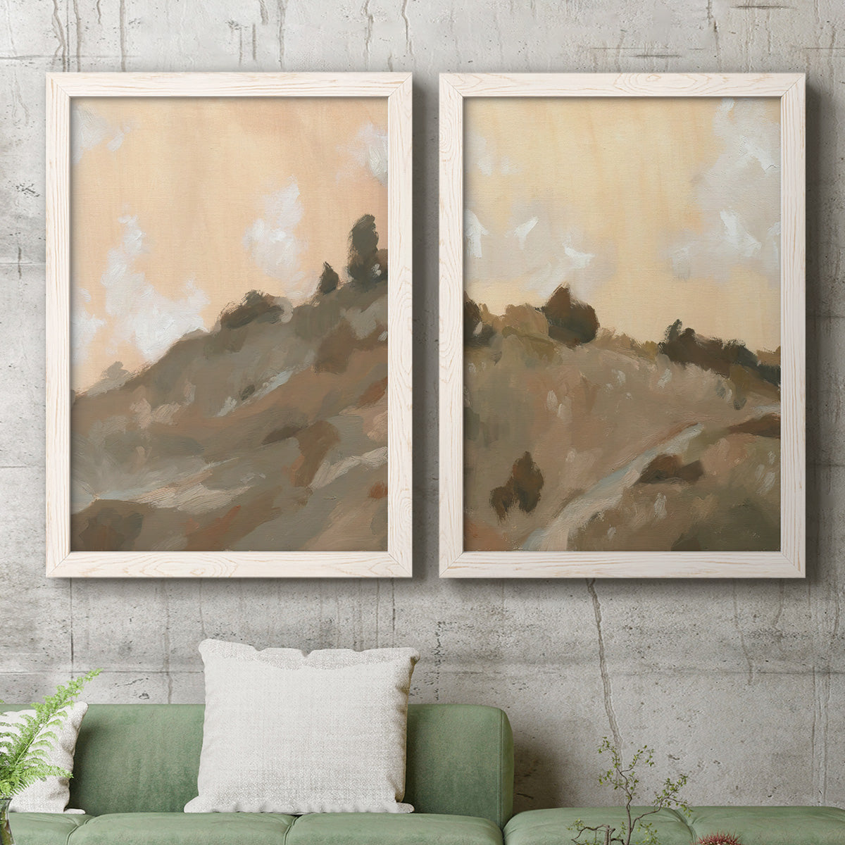 Set of two white barnwood framed canvas prints depicting a coordinated art pair of misty brown hills and winding mountain paths rendered as minimalist watercolor landscapes above a sofa in a modern living room.
