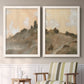 Set of two white barnwood framed canvas prints depicting two minimalist watercolor landscapes featuring misty brown hills and winding mountain paths above a sideboard in a cozy sitting room.