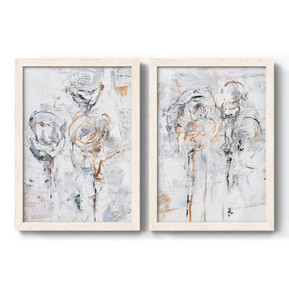 Set of two white barnwood framed canvas prints featuring two expressive floral abstracts featuring loosely suggested flowers and stems in pale gray and peach.