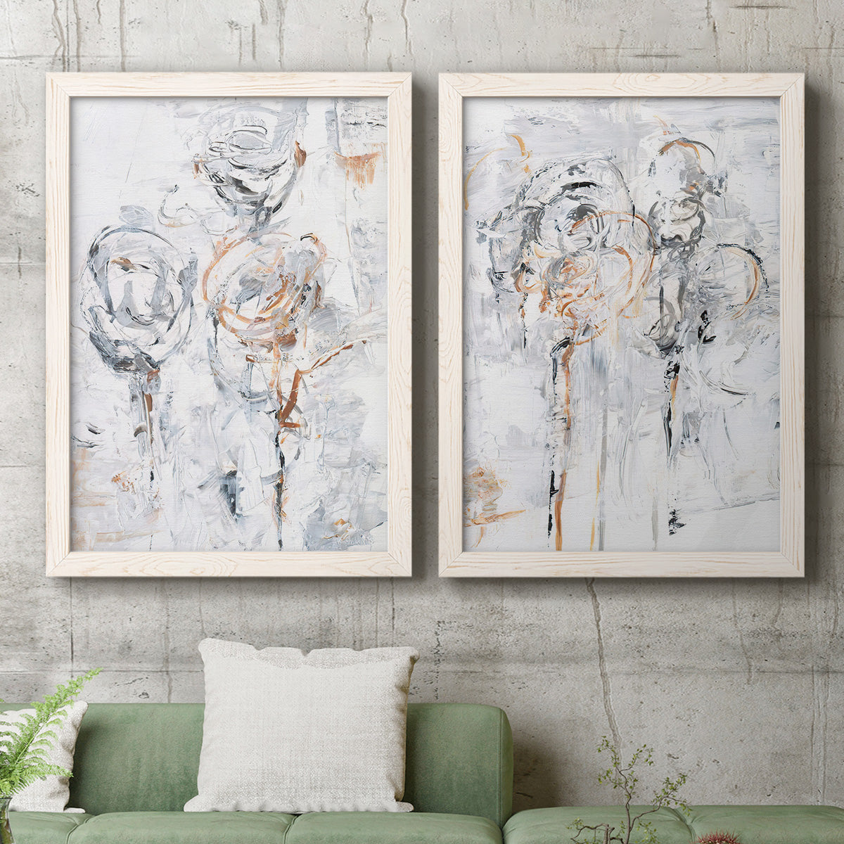 Set of two white barnwood framed canvas prints depicting a coordinated art pair of loosely suggested flowers and stems in pale gray and peach rendered as expressive floral abstracts above a sofa in a modern living room.