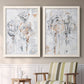 Set of two white barnwood framed canvas prints depicting two expressive floral abstracts featuring loosely suggested flowers and stems in pale gray and peach above a sideboard in a cozy sitting room.