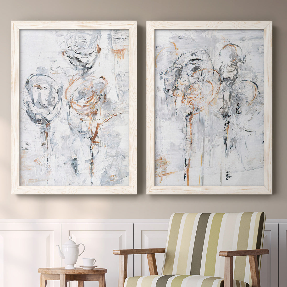 Set of two white barnwood framed canvas prints depicting two expressive floral abstracts featuring loosely suggested flowers and stems in pale gray and peach above a sideboard in a cozy sitting room.