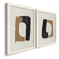Angled view of a set of two white barnwood framed canvas prints featuring two minimalist geometric collage abstracts featuring black brown and cream cutout-like forms.