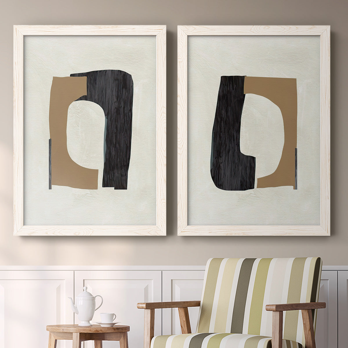 Set of two white barnwood framed canvas prints depicting two minimalist geometric collage abstracts featuring black brown and cream cutout-like forms above a sideboard in a cozy sitting room.
