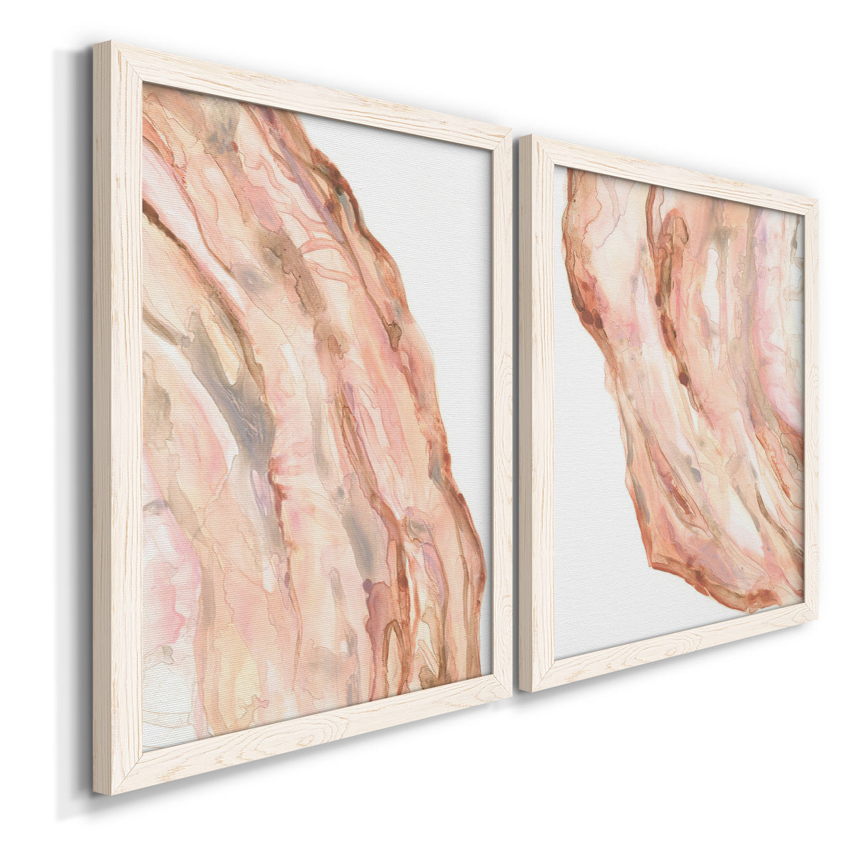 Angled view of a set of two white barnwood framed canvas prints featuring two soft marble-inspired abstracts featuring flowing blush peach and cream mineral bands.