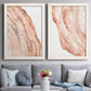 Set of two white barnwood framed canvas prints depicting paired soft marble-inspired abstracts with layered translucent striations, warm pink veins, and luminous white areas above a sofa in a contemporary living room.