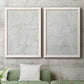Set of two white barnwood framed canvas prints depicting a coordinated art pair of faint looping handwriting across pale gray grounds rendered as minimalist script abstracts above a sofa in a modern living room.