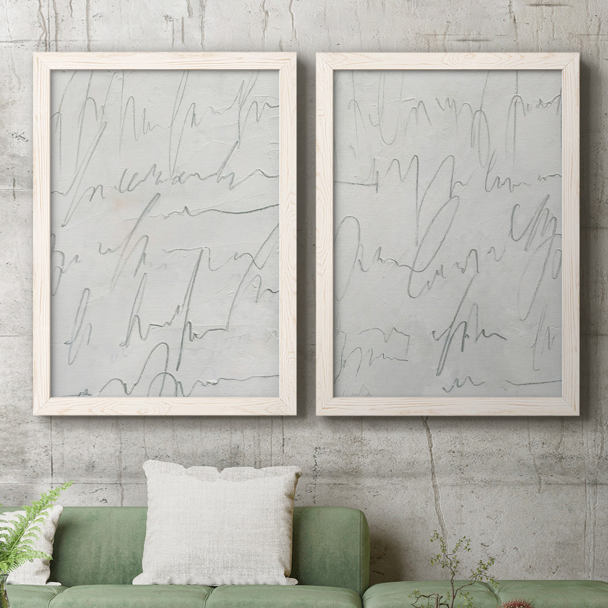 Set of two white barnwood framed canvas prints depicting a coordinated art pair of faint looping handwriting across pale gray grounds rendered as minimalist script abstracts above a sofa in a modern living room.
