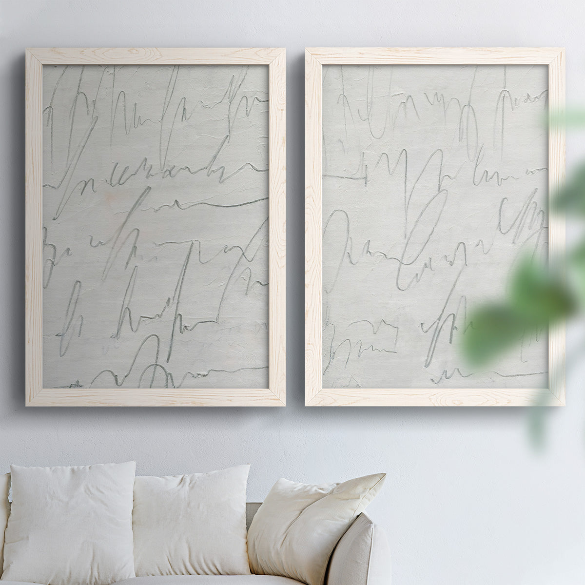 Set of two white barnwood framed canvas prints depicting thin graphite-like lines, subtle texture, and quiet monochrome fields arranged across two complementary compositions above a sofa in a bright living space.