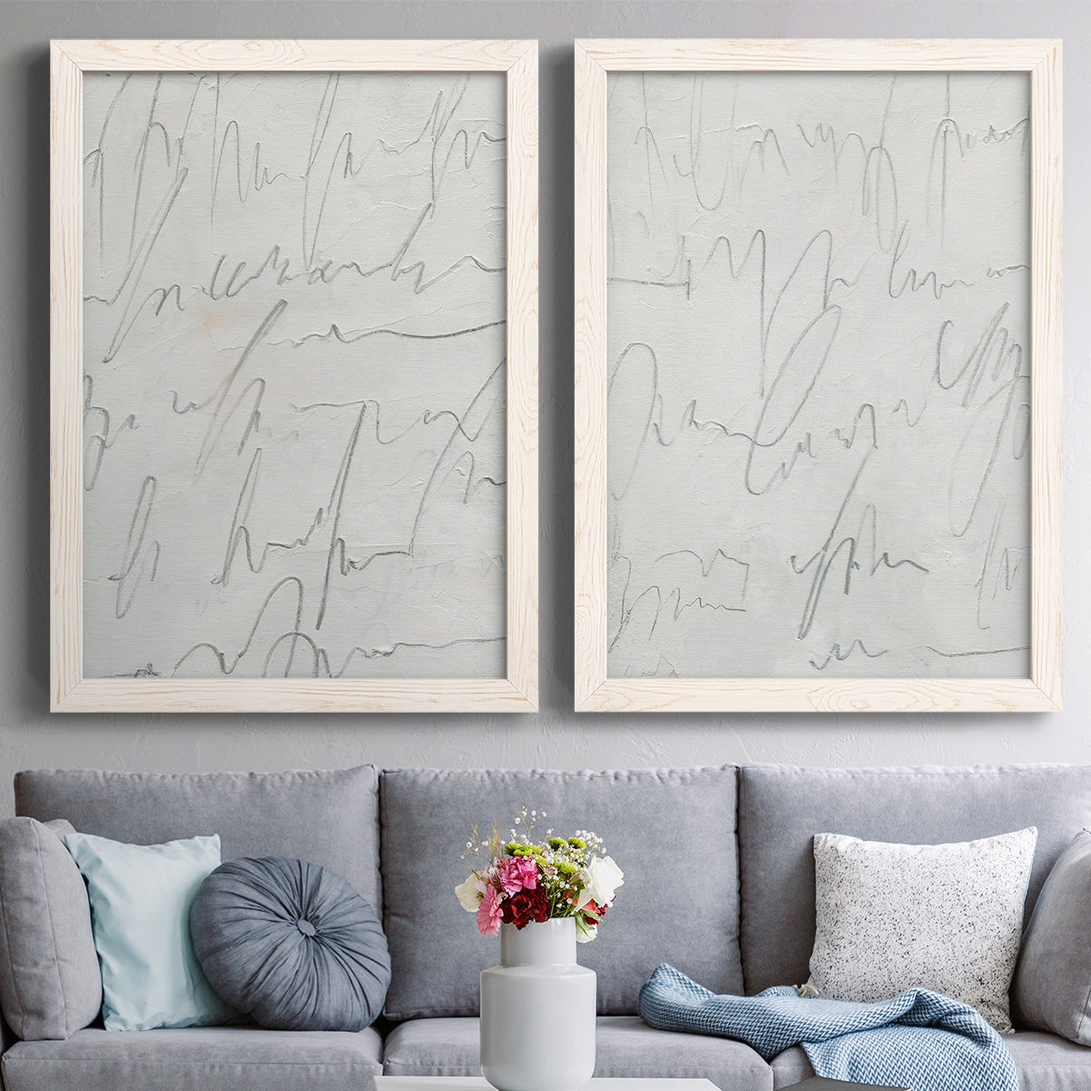 Set of two white barnwood framed canvas prints depicting paired minimalist script abstracts with thin graphite-like lines, subtle texture, and quiet monochrome fields above a sofa in a contemporary living room.