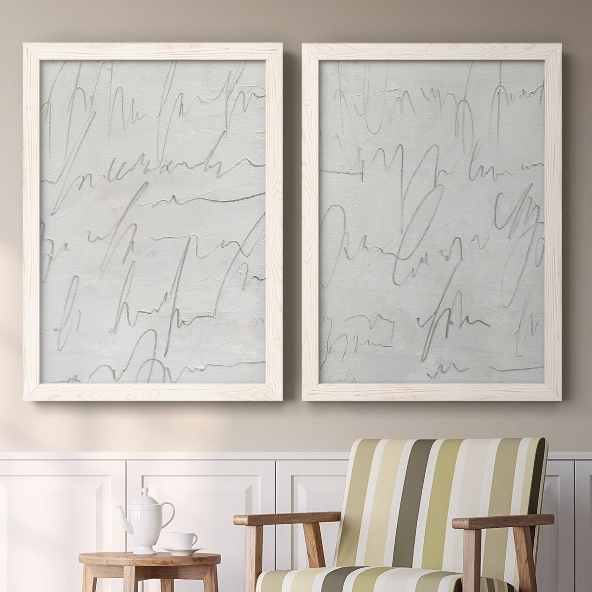 Set of two white barnwood framed canvas prints depicting two minimalist script abstracts featuring faint looping handwriting across pale gray grounds above a sideboard in a cozy sitting room.