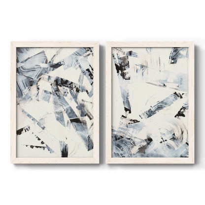 Set of two white barnwood framed canvas prints featuring two high-contrast gestural abstracts featuring angular black and gray brush fragments on white.
