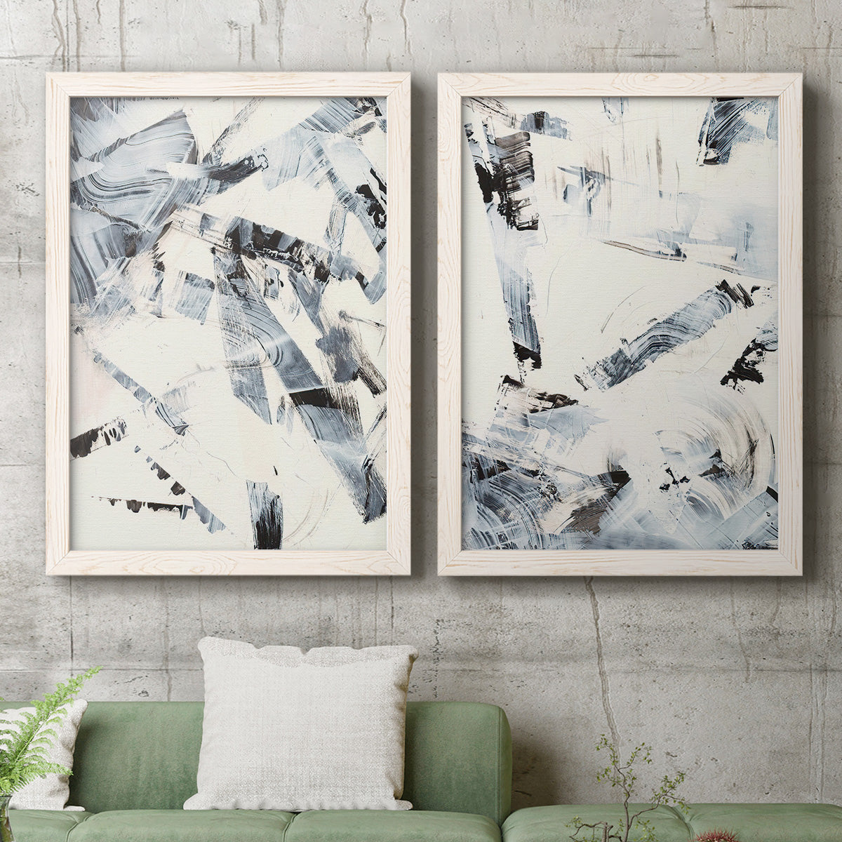 Set of two white barnwood framed canvas prints depicting a coordinated art pair of angular black and gray brush fragments on white rendered as high-contrast gestural abstracts above a sofa in a modern living room.