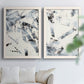 Set of two white barnwood framed canvas prints depicting broken strokes, scraped textures, and intersecting monochrome shapes arranged across two complementary compositions above a sofa in a bright living space.
