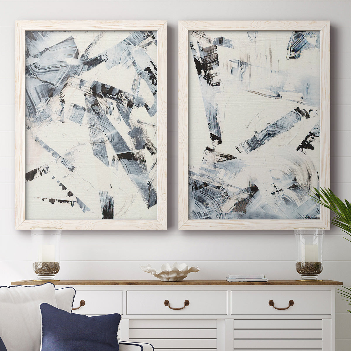 Set of two white barnwood framed canvas prints depicting a coordinated art pair of angular black and gray brush fragments on white rendered as high-contrast gestural abstracts above a dining room sideboard.