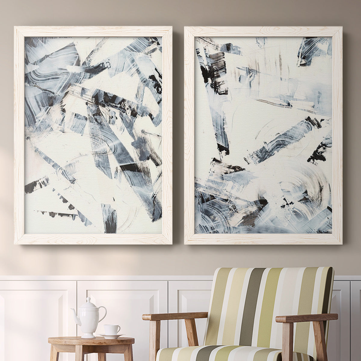 Set of two white barnwood framed canvas prints depicting two high-contrast gestural abstracts featuring angular black and gray brush fragments on white above a sideboard in a cozy sitting room.