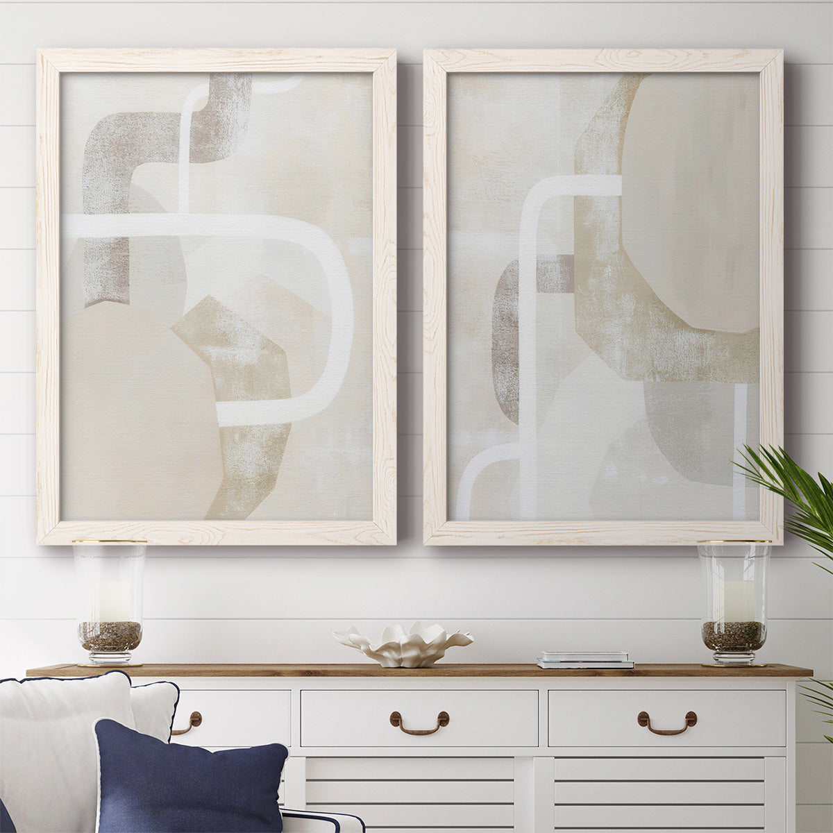 Set of two white barnwood framed canvas prints depicting a minimalist abstract pair of layered curves blocks and sweeping white linear shapes above a dining room sideboard.