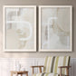 Set of two white barnwood framed canvas prints depicting two neutral geometric abstracts with overlapping rounded forms white lines and soft beige gray textures above a sideboard in a cozy sitting room.