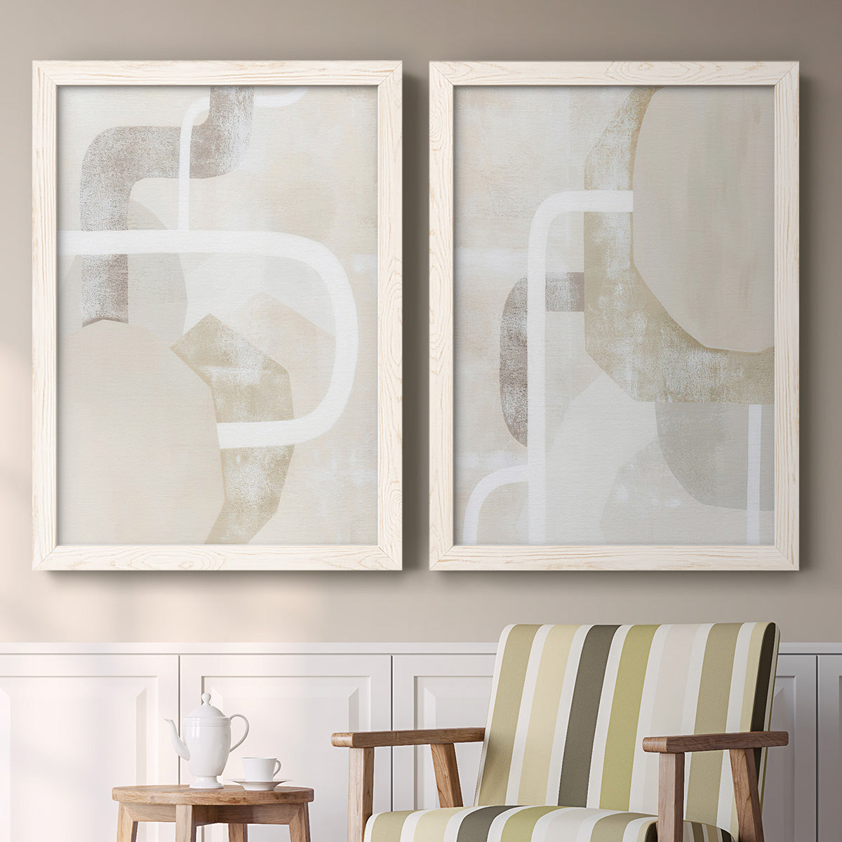 Set of two white barnwood framed canvas prints depicting two neutral geometric abstracts with overlapping rounded forms white lines and soft beige gray textures above a sideboard in a cozy sitting room.